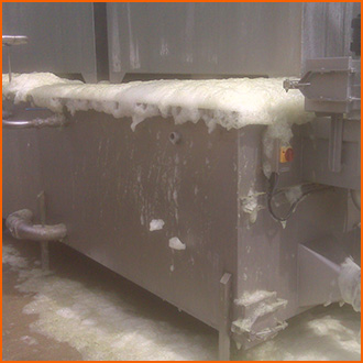 A vegetable washing tank overflows with foam